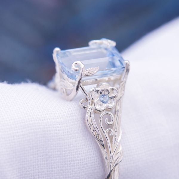 The aquamarine in this delicate, leafy ring is held in place by bits of vining that seem to grow up and over the center stone.