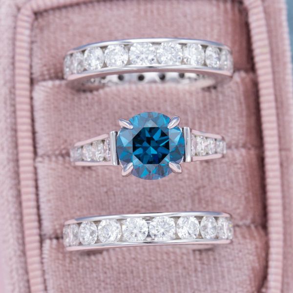 The clean lines of three channel-set diamond and white gold bands allow the blue diamond to take the spotlight in this bridal set.