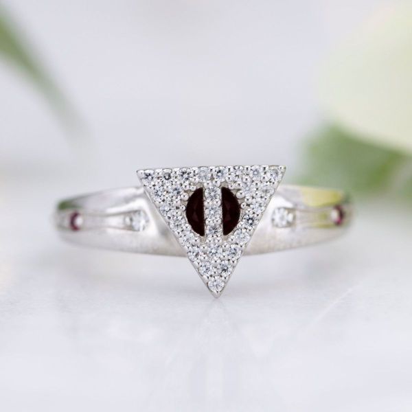 Dozens of moissanites dazzle in this engagement ring with a prominent Deathly Hallows inspired logo and Elder Wand detailing in the band.