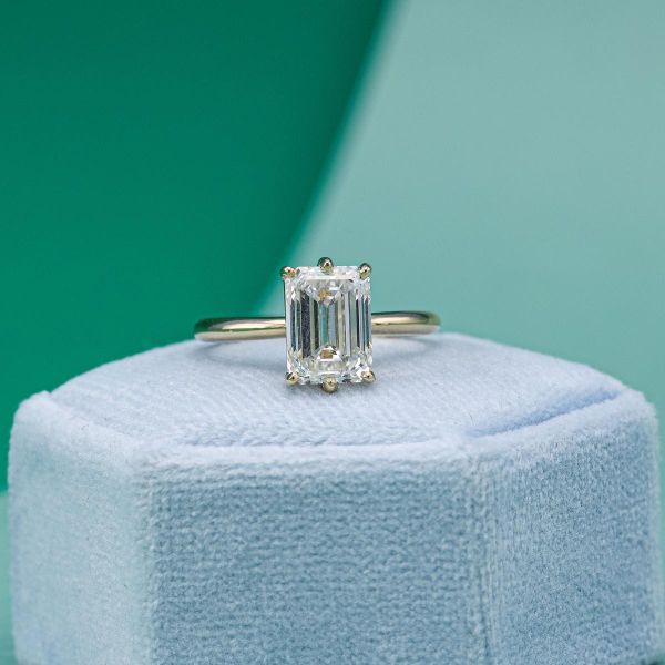 A simple engagement ring in yellow gold with an emerald cut lab diamond taking center stage.
