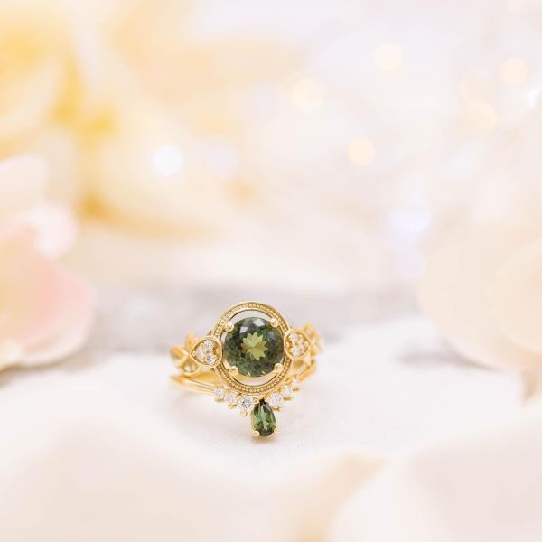 Green tourmaline engagement ring with a floating beaded halo and diamond accents and a matching tiara wedding ring.