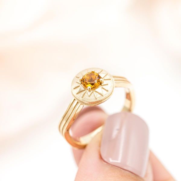 以太阳为灵感设计的订婚戒指，中间镶有一颗柠檬黄宝石。