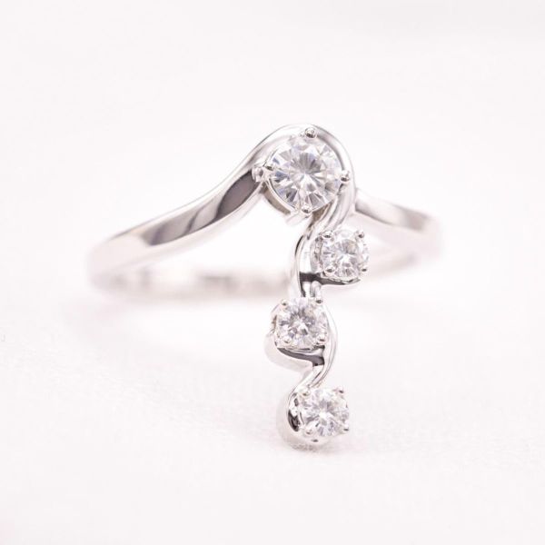 这枚独特戒指上的钻石悬挂在精致的白金缎带上，沿着佩戴者的手指垂下。