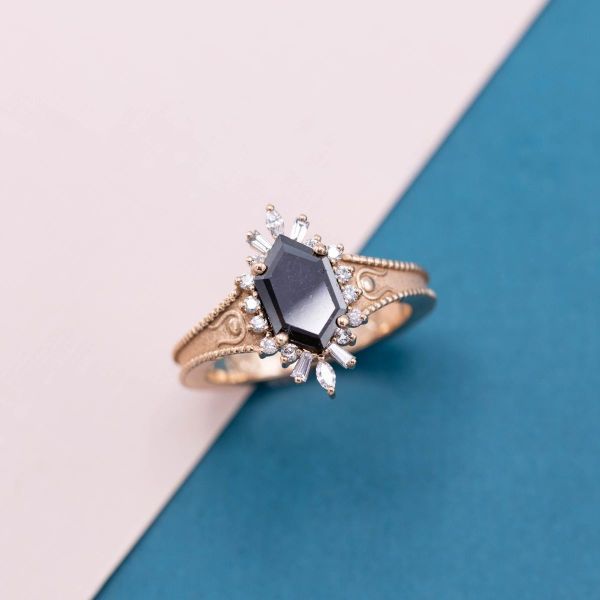 这枚订婚戒指上有六边形切割的黑钻石星星，还有芭蕾舞演员光环和玫瑰金串珠戒指。