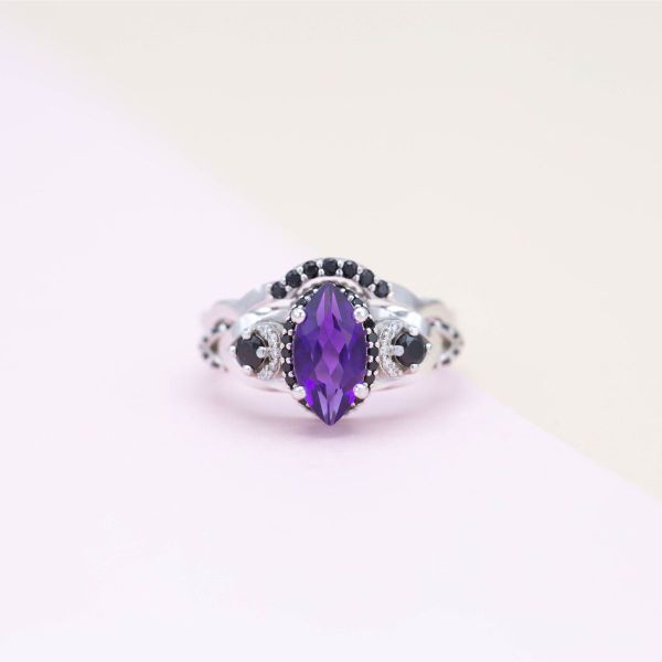 A marquise cut amethyst sits between black spinel and diamond accents.