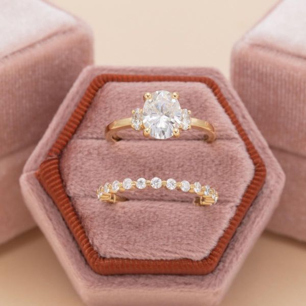 An oval moissanite with accent side stones in a yellow gold setting.