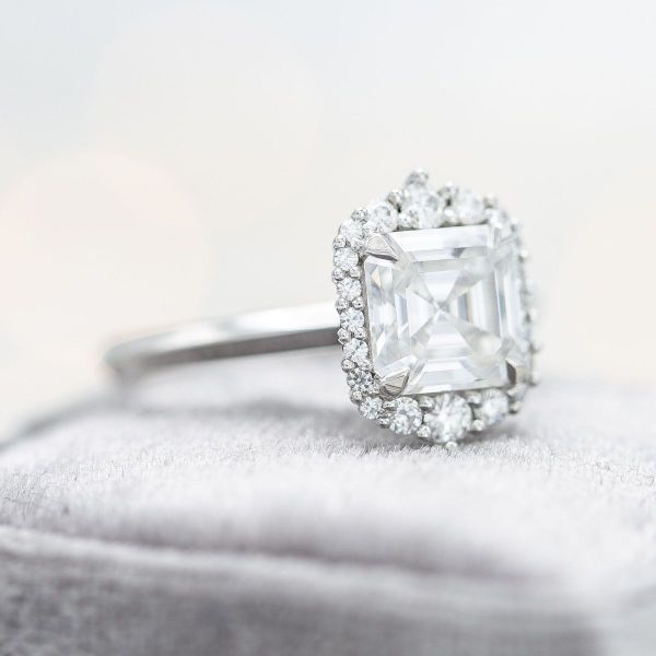 The Asscher cut center stone and halo combination of this moissanite and white gold engagement ring creates a vintage vibe.