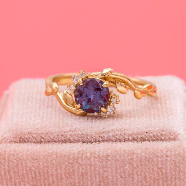 This round alexandrite has a purple hue in this lighting with diamond accents and a nature inspired yellow gold band.