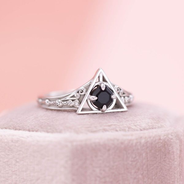 This deathly hallows inspired engagement ring features a jet-black onyx center stone, resembling the resurrection stone.