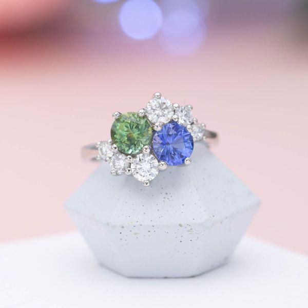 “An engagement ring must feature only one stone” said no one ever! These medium blue and medium green Montana sapphires create an alluring two-tone base for a stunning cluster ring, completed by brilliant diamond accents and a simple platinum band.
