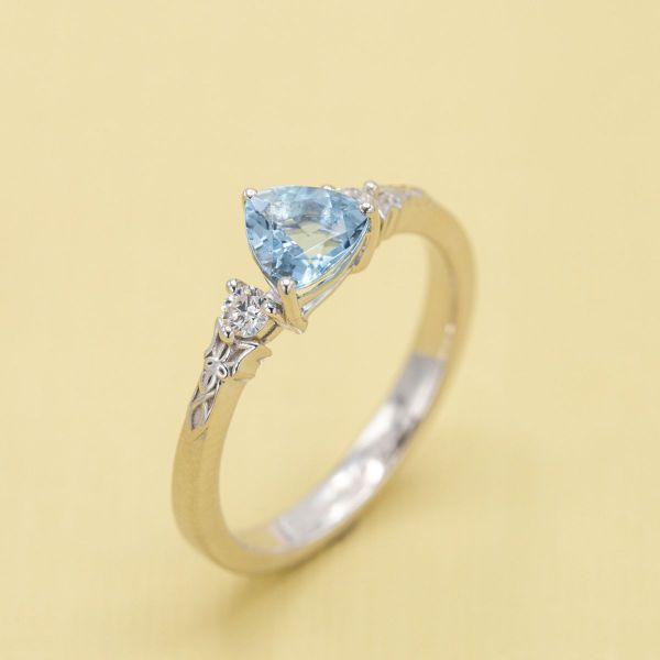 The trillion cut aquamarine stone is paired with diamond accents in this engagement ring.
