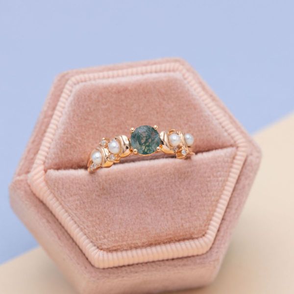A round moss agate sits between a pavé of pearls in this engagement ring.