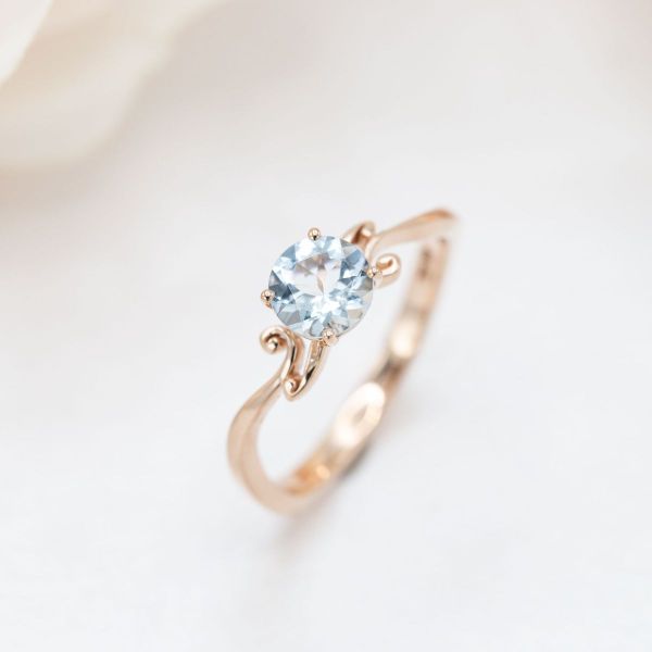 A lightly saturated aquamarine sits inside a whimsical yellow gold band.