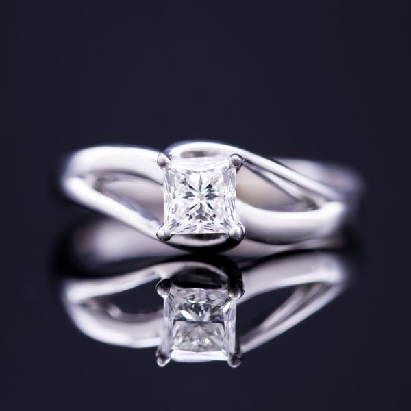 The perfect contrast: bold, sweeping arms of white gold frame the sharp angles of a princess cut diamond center stone.