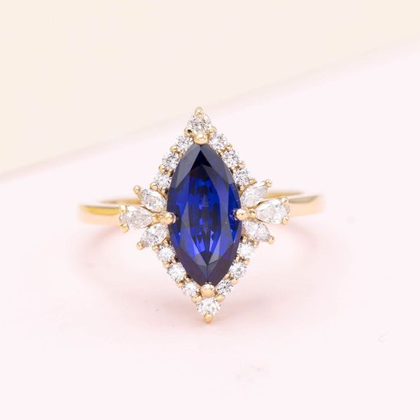A work of art! This extraordinary marquise cut lab-created sapphire deserves an extraordinary halo. The diamond halo enhances the elongated shape of the ring, with a handful of pear and marquise cut accents mimicking the shape of an antique frame.