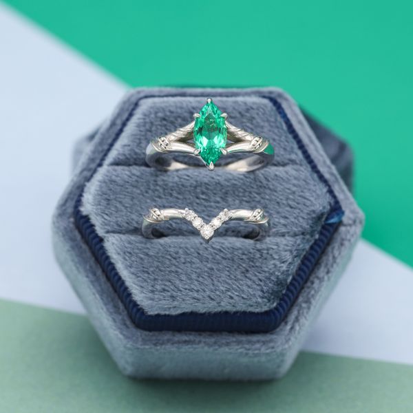 This lightly saturated marquise cut emerald has blue undertones and sits in a white metal split-shank band.