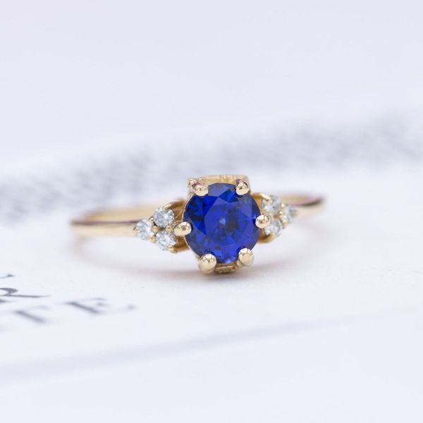 Subtle personalizations tell a love story on this lab created sapphire and diamond engagement ring with a trumpet and rose peekaboo.