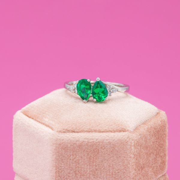 A toi et moi engagement ring features two pear shaped emeralds.