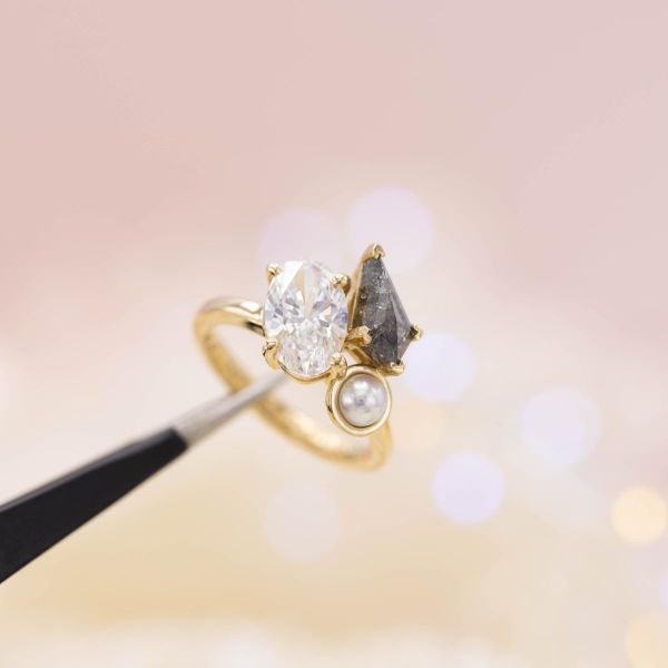 The cluster on this yellow gold ring features a salt and pepper diamond, white diamond, and white pearl.