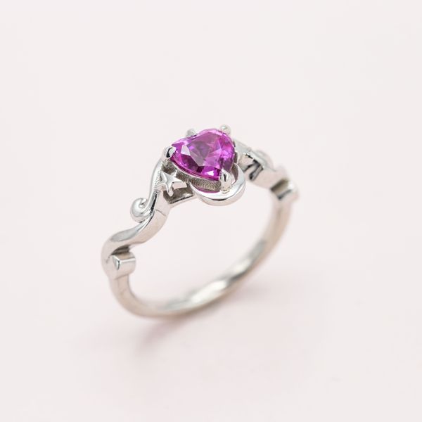 A heart-shaped pink sapphire is embraced by the moon and stars.