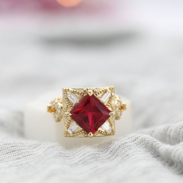 A bold, vintage-inspired gold ring with a kite-set ruby and unique baguette halo.