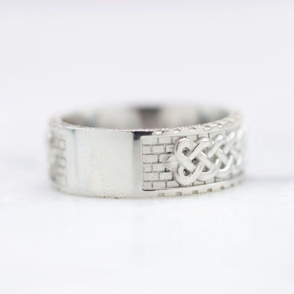This platinum wedding band features a dire wolf inspired centerpiece with a brick background and Celtic sailor’s knots.