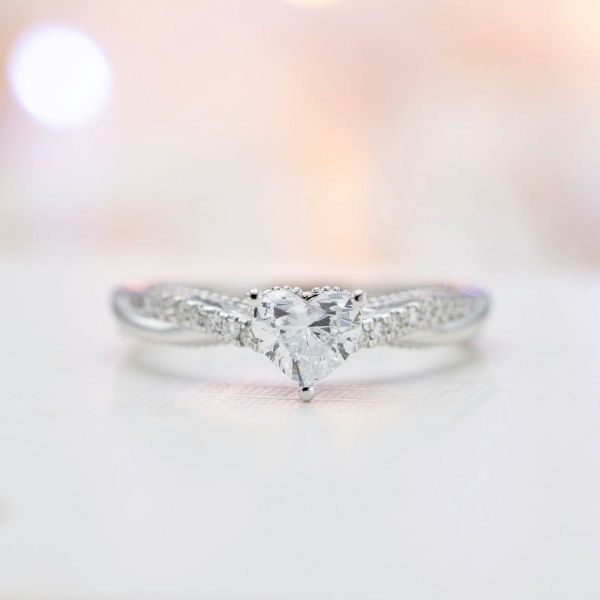Pavé diamond twists give a slinky look to this heart cut diamond centered engagement ring.