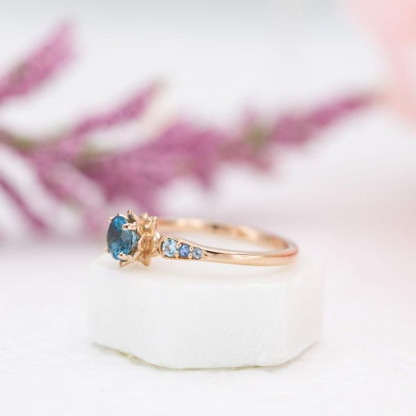 This blue themed lotus engagement ring uses a topaz as its center stone.