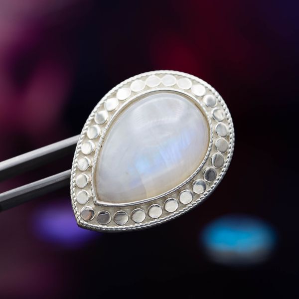 This large brooch features a beaded rim around a pear-cut moonstone cabochon.