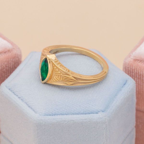 A yellow gold band surrounds this beautiful lab-created emerald.