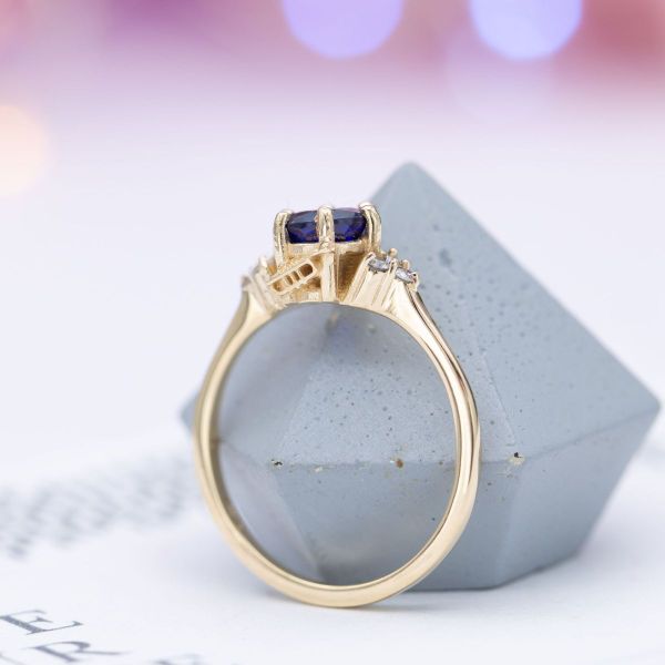 Subtle personalizations tell a love story on this lab created sapphire and diamond engagement ring with a trumpet and rose peekaboo.