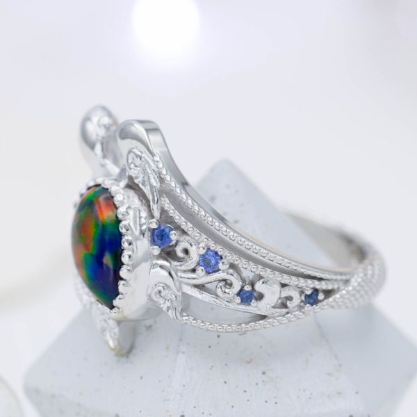 A pear cut black opal set as the shell of this turtle engagement ring with a guitar string-inspired band.