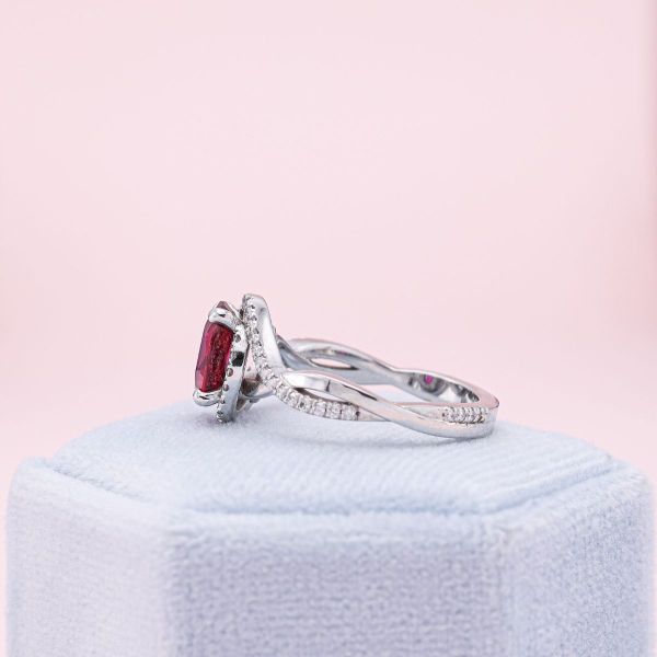 An oval cut ruby nestles on a twisted white gold band with diamond accents