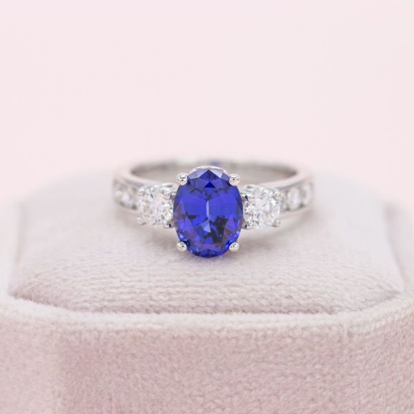 Channel-set diamond accents add sparkle to this sapphire and diamond three stone ring.