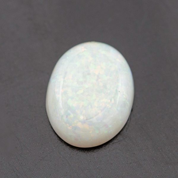 椭圆形的白色蛋白石，带有彩色火焰的斑点。