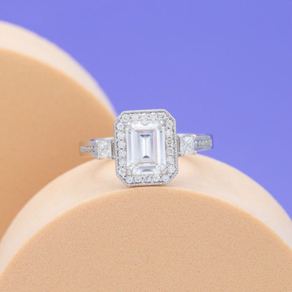 A haloed emerald cut moissanite gives vintage vibes in this engagement ring while the channel-set moissanite white gold band pulls this ring into modern times.