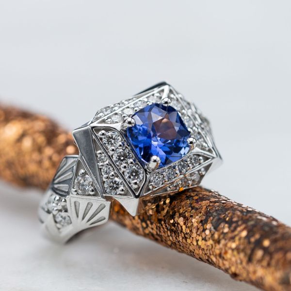 这枚大胆的装饰艺术风格蓝宝石订婚戒指用三角形创造了一个旋转的几何光环。