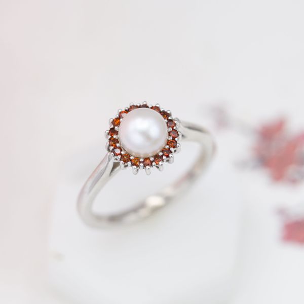 Another striking color contrast, with a sunburst halo of garnets framing the pearl center stone.