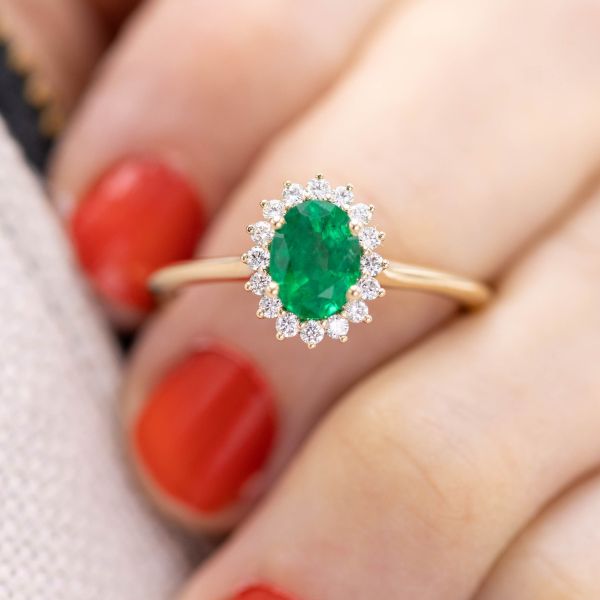 This natural emerald is the center of a yellow gold engagement ring with a diamond halo.
