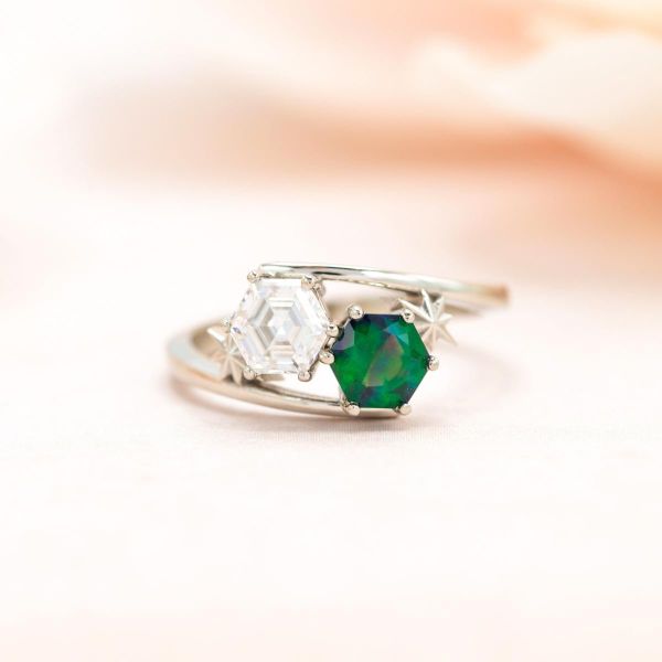 Two stone engagement ring with hexagon-cut moissanite and green-hued opal in a sweeping bypass setting.