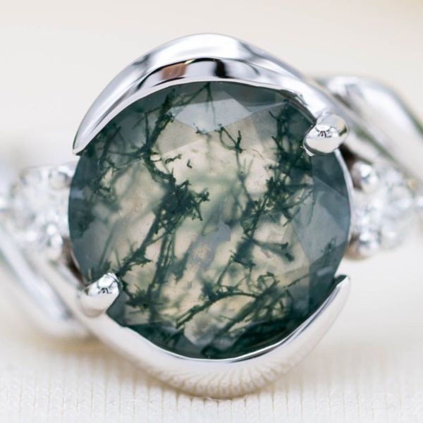 A close-up look at a moss agate, with vivid green inclusion tendrils, in a white gold setting.