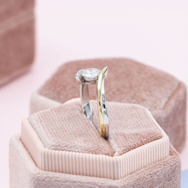 The sweeping lines of this two-tone white and yellow gold band make this engagement ring’s faux tension-set moissanite appear to float.