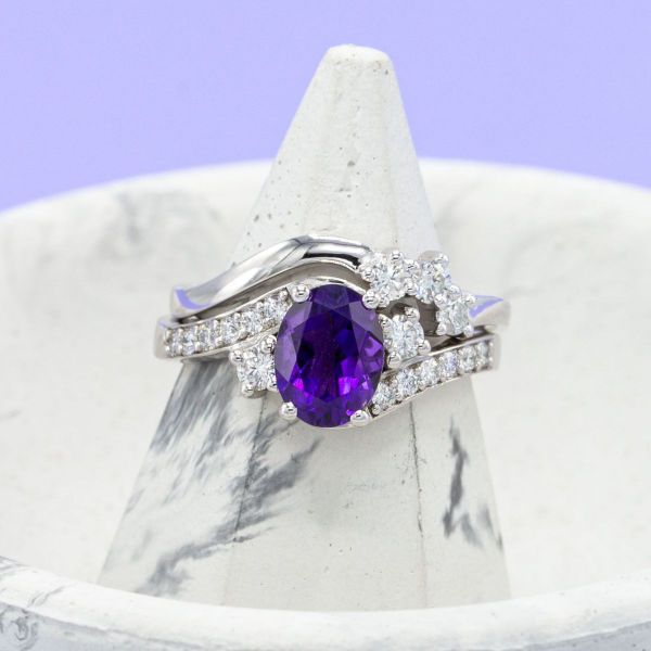 An oval amethyst brings a regal feel to this white gold engagement ring dotted with no shortage of diamond accents.