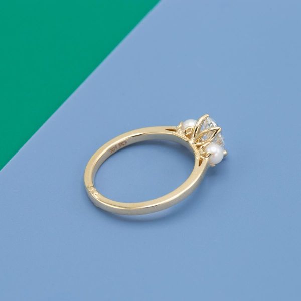 Two pearls flank the diamond in the center of this yellow gold ring.