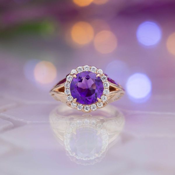A brilliant round amethyst is surrounded by a diamond halo with a rose gold split shank setting.