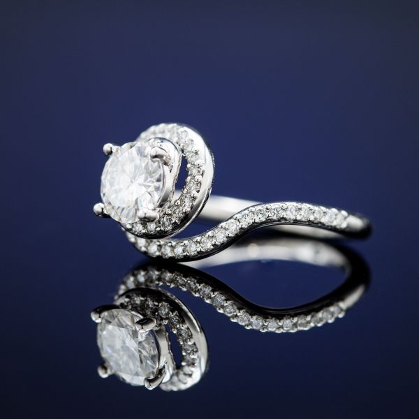 Elegantly curving twist of pave white gold spirals around a prong-set moissanite center stone.