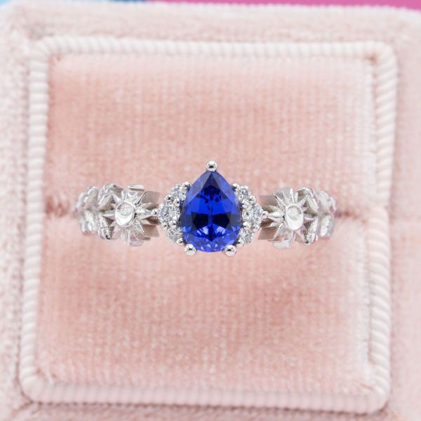 The lab-created pear cut sapphire and diamond accents at the center of this unique ring almost look as if they are floating! The center setting barely touches the white gold band of the ring which incorporates natural elements.