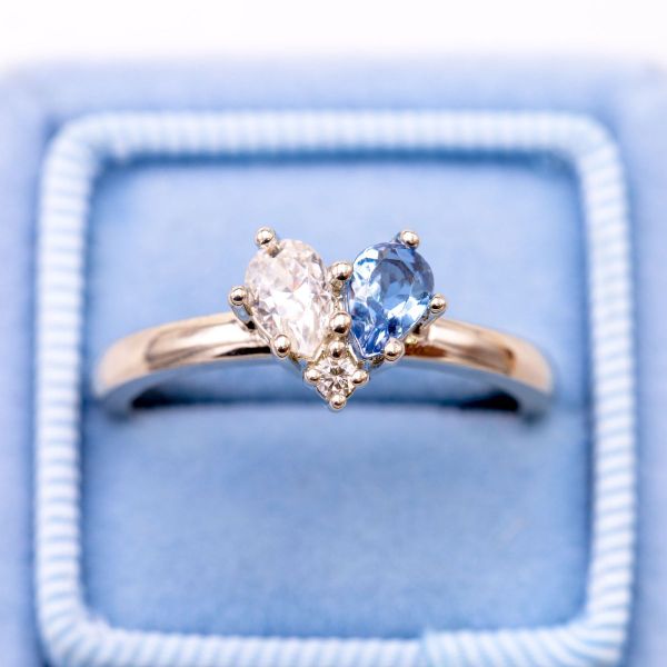 Two pear cut stones fit together to create one heart in this stunning moissanite and aquamarine engagement ring.