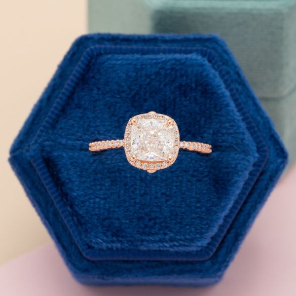 The diamond at the center of this rose gold engagement ring is a lab created diamond.