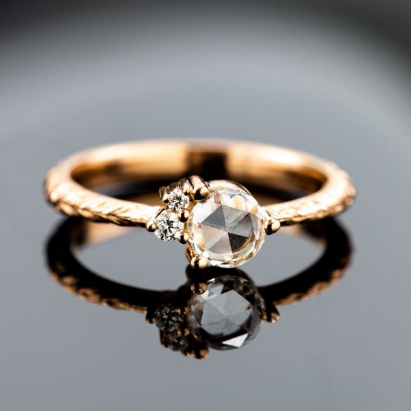 一个简单的玫瑰切割钻石搭配两个较小的钻石，创造一个引人注目的集群。